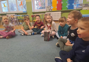 Dzieci siedzą na dywanie i śpiewają