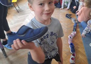 Chłopiec pozuje do zdjęcia z butem