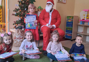 Grupa dzieci pozuje do zdjęcia ze Świętym Mikołajem na tle choinki