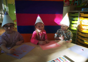 Dzieci wykonują rysunek, korzystając z kredek.