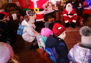 Dzieci siedzą w domku Świetego Mikołaja