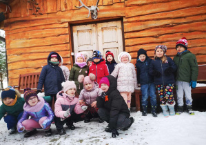 Dzieci pozują grupowo na tle drewnianej chatki