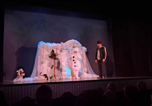 Scena w teatrze - aktor Bajarz i Bałwan w tle dekoracja zimowej krainy