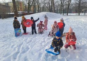 Grupa dzieci pozuje do zdjęcia ze sprzętem do zabaw na śniegu