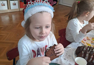 Dziewczynka siedzi przy stole i je ciasto piernikowe