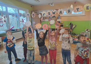 Grupa dzieci pozuje do zdjęcia z ilustracjami pączków
