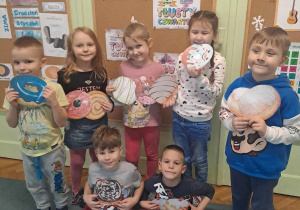 Grupa dzieci pozuje do zdjęcia z ilustracjami pączków