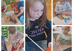 Dzieci siedzą przy stolikach i wykonują pracę plastyczną farbami