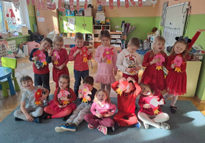 Grupa dzieci ubranych na czerwono pozuje do zdjęcia z papierowymi rakietami