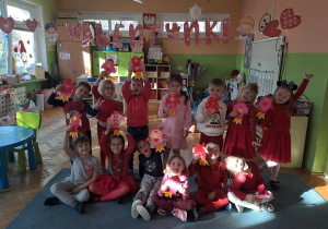 Grupa dzieci ubranych na czerwono pozuje do zdjęcia z papierowymi rakietami