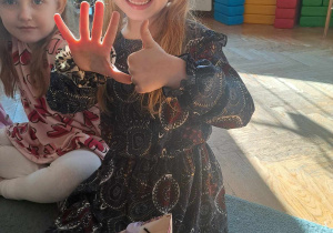 Dziewczynka uśmiecha się do zdjęcia i pokazuje na palcach, że kończy 6 lat