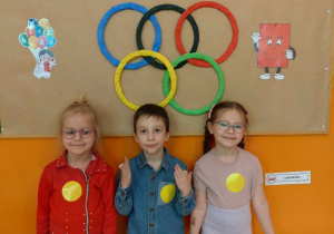Drużyna dzieci pozuje do zdjęcia w tle napis Olimpiada Matemetyczna