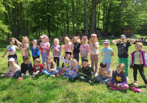 Grupa dzieci pozuje do zdjęcia na tle zielonych drzew