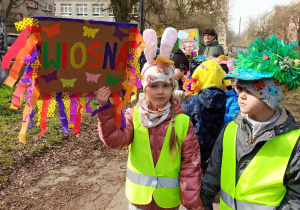 Dzieci maszerują po okolicy z transparentami witając wiosnę
