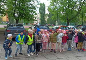 Dzieci ubrane w kurtki i buty idą do sąsiedniej szkoły na przedstawnie