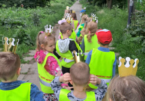 Dzieci ubrane w kamizelki odblaskowe i korony wracają do przedszkola