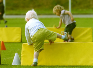 Dziecko w białej bluzce i jasnych włosach pokonuje tor przeszkód