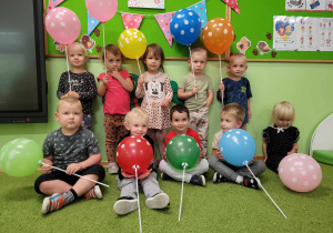 Cała grupa pozuje do zdjęcia trzymając kolorowe balony w kropki