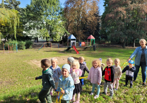 Dzieci spacerują , trzymając się weża do nauki chodzenia w parach