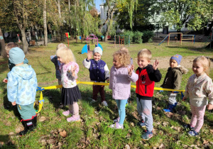 Dzieci spacerują , trzymając się weża do nauki chodzenia w parach