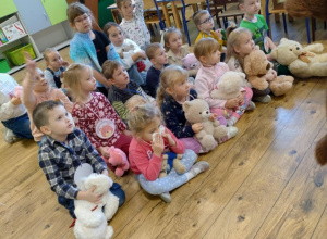 Dzieci siedzą w siadzie skrzyżnym na podłodze.