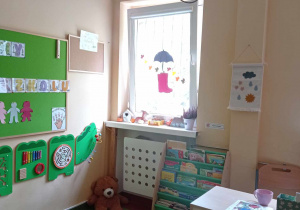Sala przedszkolna grypy dzieci 3 i 4 letnich - dywan, pluszowy miś, biurko nauczyciela, dekoracje jesienne w oknach