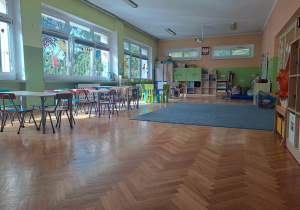 Sala przedszkolna grypy dzieci 5 letnich - stoły, krzesła, okna z dekoracjami, szafy