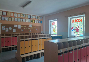 Szatnia przedszkola - kolorowe szafki, jesienne dekoracje na oknach, tablice korkowe z dekoracjami, dyplomy i certyfikaty
