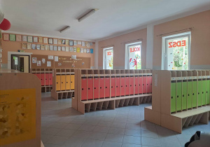 Szatnia przedszkola - kolorowe szafki, jesienne dekoracje na oknach, tablice korkowe z dekoracjami
